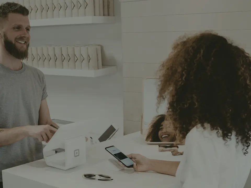 Mostrador de una tienda con terminal de pago y cliente completando una compra